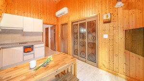 A wooden interior with a kitchen area, including cabinets, a stove, and a dining table with flowers. - Gapyeong Sanchaek Glamping Pension (Gapyeong)