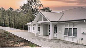 A modern building with a sloped roof, large windows, and a gravel driveway. - Luxury Home for Work Teams and Families (Muswellbrook)