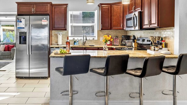 A modern kitchen with stainless steel appliances, wooden cabinets, and a central island with bar stools.