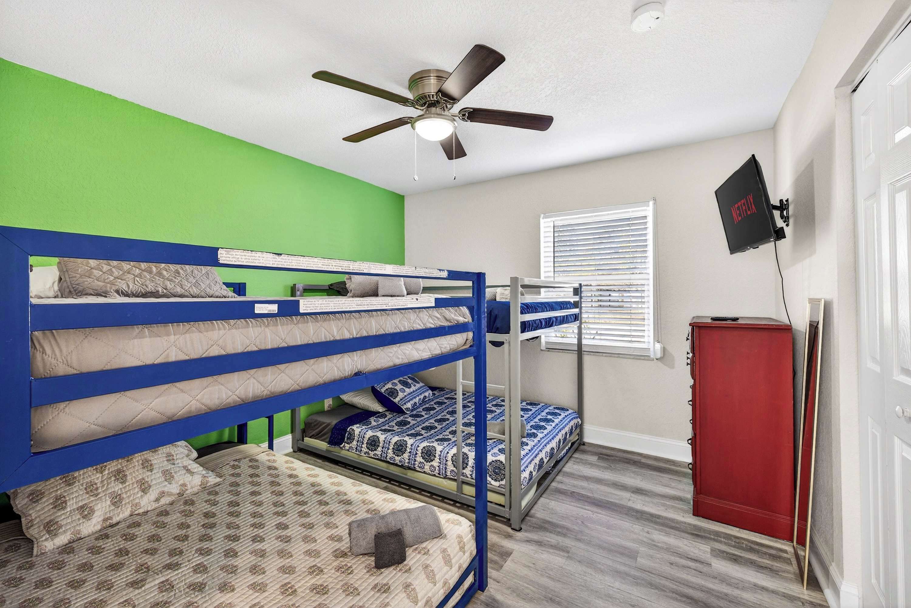 A bunk bed room with a ceiling fan, a red cabinet, and a wall-mounted Netflix sign.
