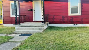 A red house with a white door, a small porch, and a satellite dish.