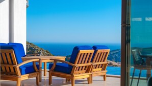 A wooden outdoor seating area with blue cushions, overlooking a scenic coastal view. - Breathtaking views of Kalkan Bay await you (Kalkan Centre)