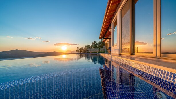 An infinity pool with a clear view of the sunset and mountains in the background. - Breathtaking views of Kalkan Bay await you (Kalkan Centre)