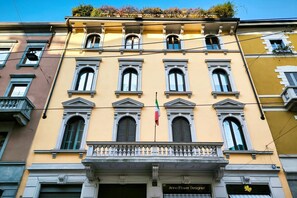A building with a yellow facade, multiple windows, and a balcony. - Hostmate - Milano - Magenta - Cadorna  (Milano)