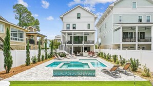 Ein zweistöckiges Haus mit Schwimmbad und einer Terrasse, auf der Liegestühle stehen.