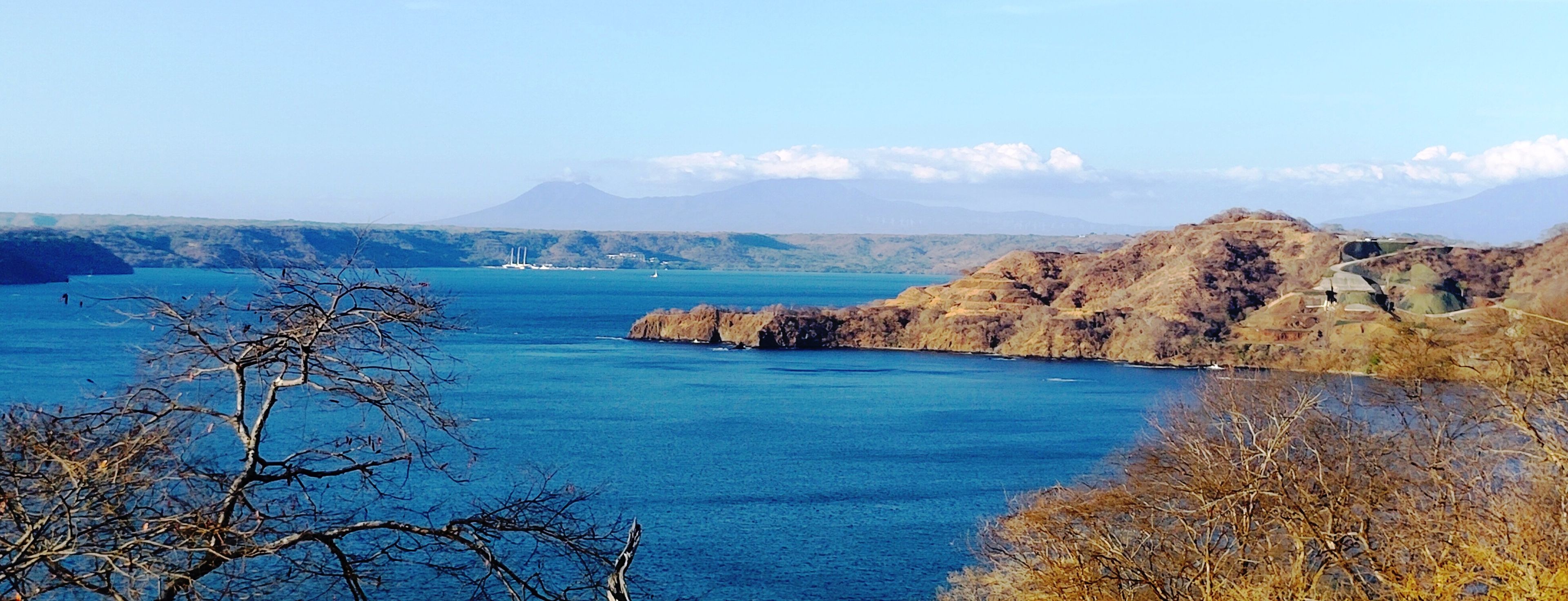 Eine Küstenlandschaft mit freiem Blick auf das Meer, felsigem Gelände und entfernten Bergen.