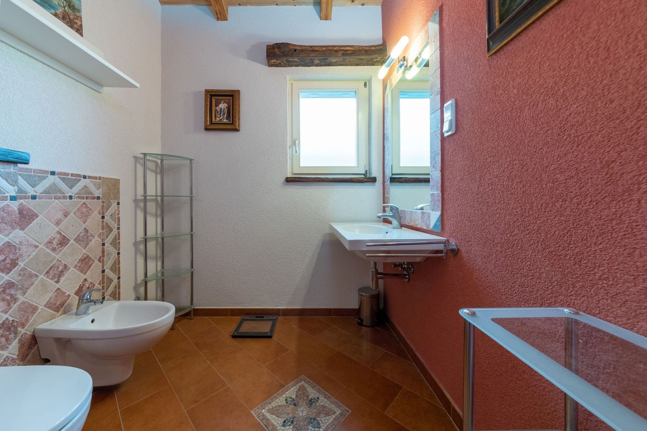 A bathroom with a toilet, bidet, sink, and a glass shower enclosure.