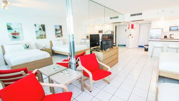 A hotel room with a bed, a desk, a TV, and a dining area with chairs.