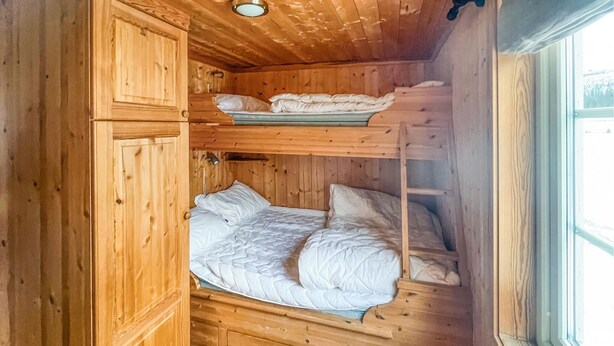 A wooden cabin with bunk beds, a window, and a door.
