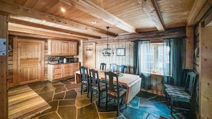 A rustic wooden interior with a dining area, kitchen, and a large window.