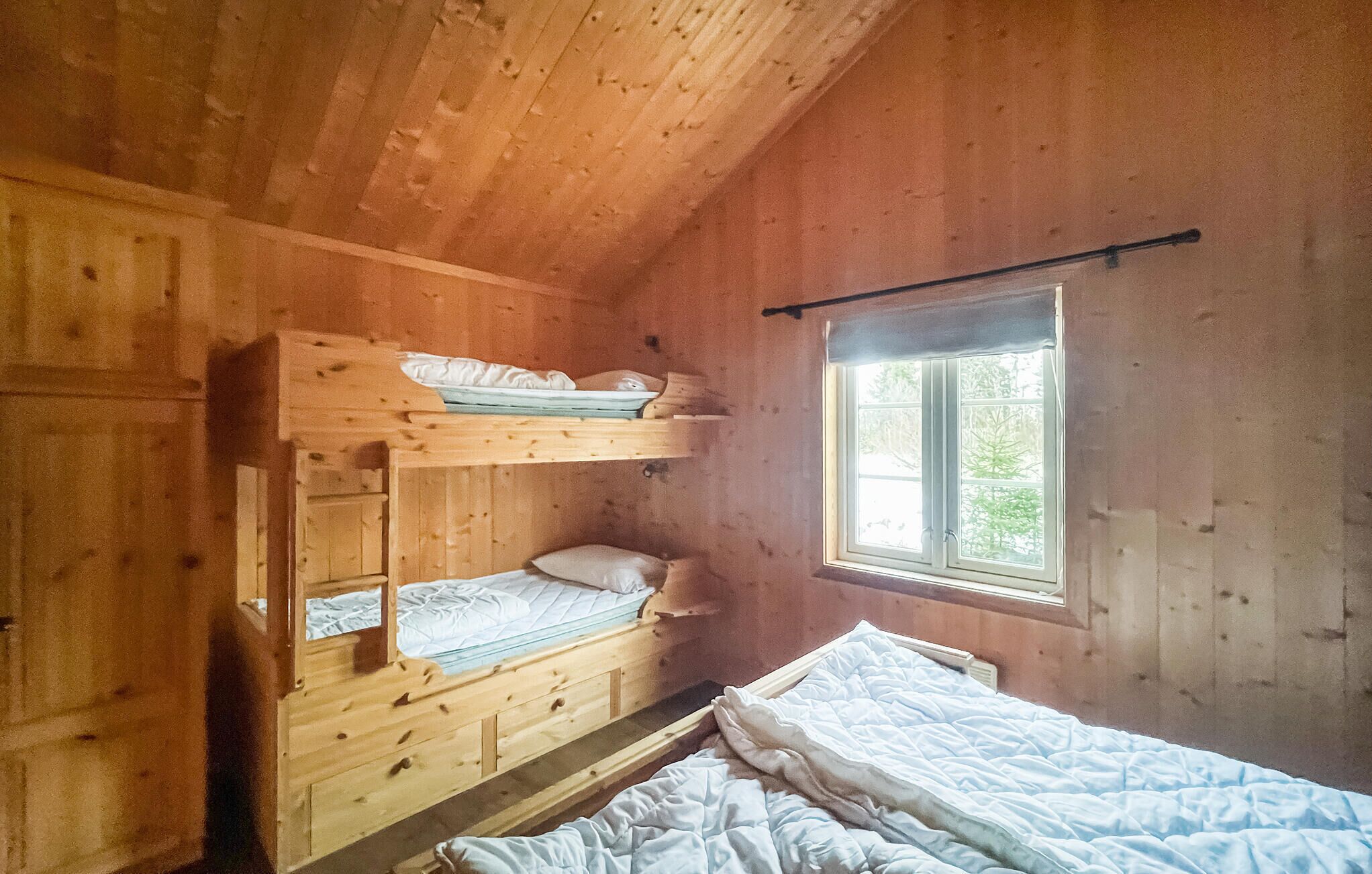 A cabin with bunk beds, a window with a view, and wooden walls.
