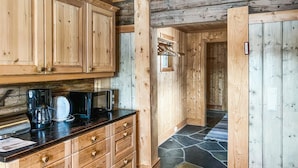 A wooden interior with a kitchen area featuring cabinets, a countertop with a coffee maker, toaster, and microwave.
