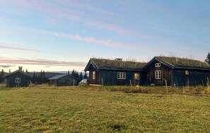 Un entorno rural con edificios de madera, un campo cubierto de hierba y un cielo despejado.