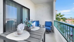 Ein Balkon mit Tisch, zwei Stühlen, einem Blumentopf und einem Fenster.