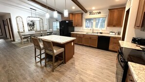 A spacious kitchen with wooden cabinets, a central island with seating, and pendant lighting.
