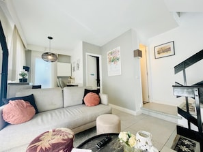 A modern living room with a sofa, ottoman, coffee table, and a staircase.