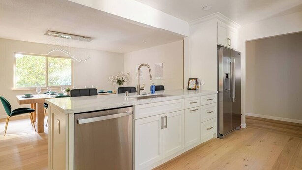 Una cocina moderna con lavavajillas incorporado, electrodomésticos de acero inoxidable y un comedor con vistas al exterior.