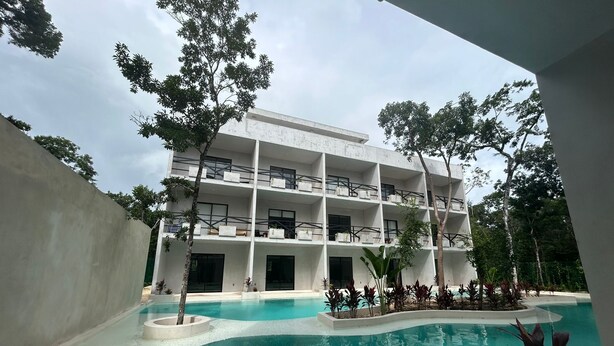 A multi-story hotel with a swimming pool and surrounding greenery. - Tulum Ayook apartment with Starlink (Tulum)