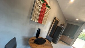 A modern kitchen with a wooden table and chairs, a black vase, and a colorful wall hanging. - Tulum Ayook apartment with Starlink (Tulum)