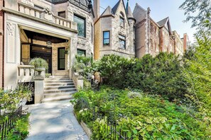 Un edificio histórico con fachada de piedra, una entrada imponente y un jardín exuberante.