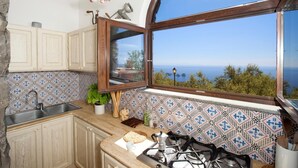 Cocina con vistas al mar, una estufa, un fregadero y una ventana.