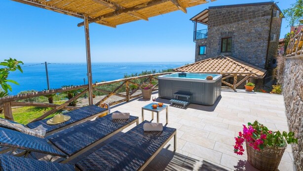 Una terraza en la azotea con mobiliario exterior, una bañera de hidromasaje y vistas al mar.