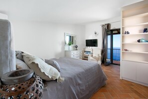A bedroom with a bed, a TV, a dresser, and a balcony with a view. - Casa dei Limoni - peaceful retreat with sea views (Massa Lubrense)