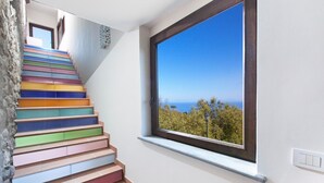 Una escalera con peldaños de colores que conduce a un balcón con vista al mar.