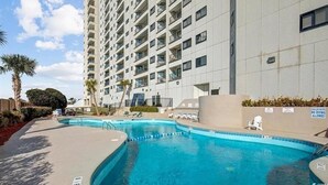 Un immeuble de grande hauteur doté d’une piscine et de chaises longues.
