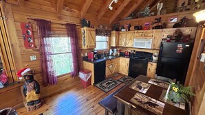 A cozy cabin-style kitchen with wooden walls and a wooden ceiling, featuring a stove, sink, and refrigerator. - Honeymoon log cabin with heart shaped whirlpool Tub & Hot Tub on Covered Porch (Sevierville)