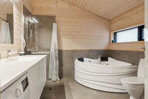 A modern bathroom with a white bathtub, a toilet, a sink, and a shower.