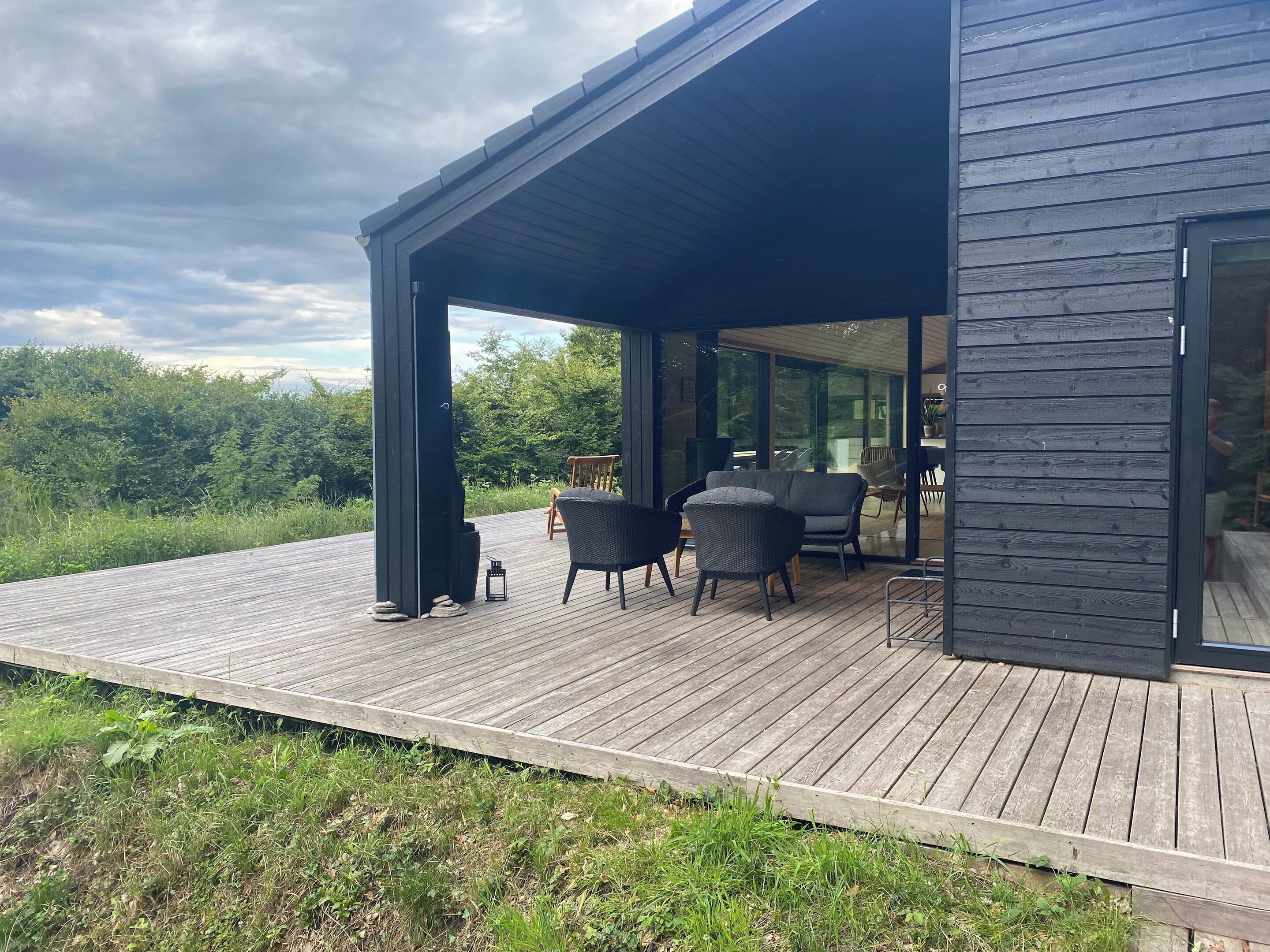 Un espace extérieur abrité, aménagé avec des chaises et une table, et offrant une vue sur un paysage naturel.