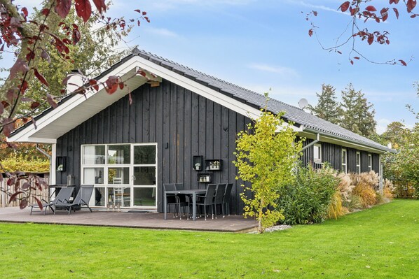 A modern house with a large deck, a dining area, and a garage.