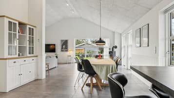 A spacious kitchen with a dining area, white cabinetry, and a large window.