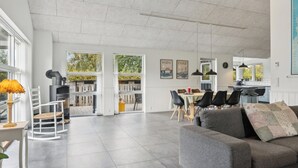 Een ruime woonkamer met een open haard, een eettafel en moderne meubels.