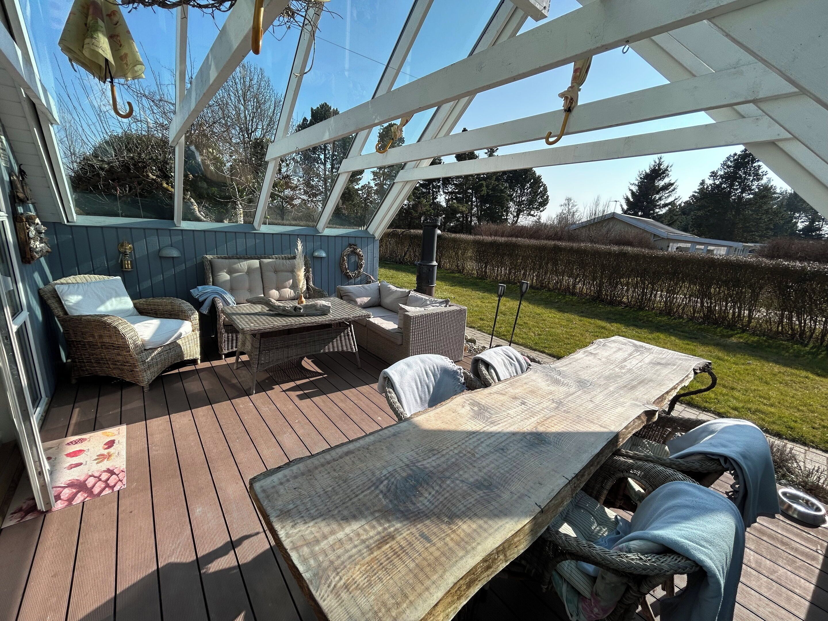 A covered outdoor deck with wicker furniture, a table, and a hanging umbrella.
