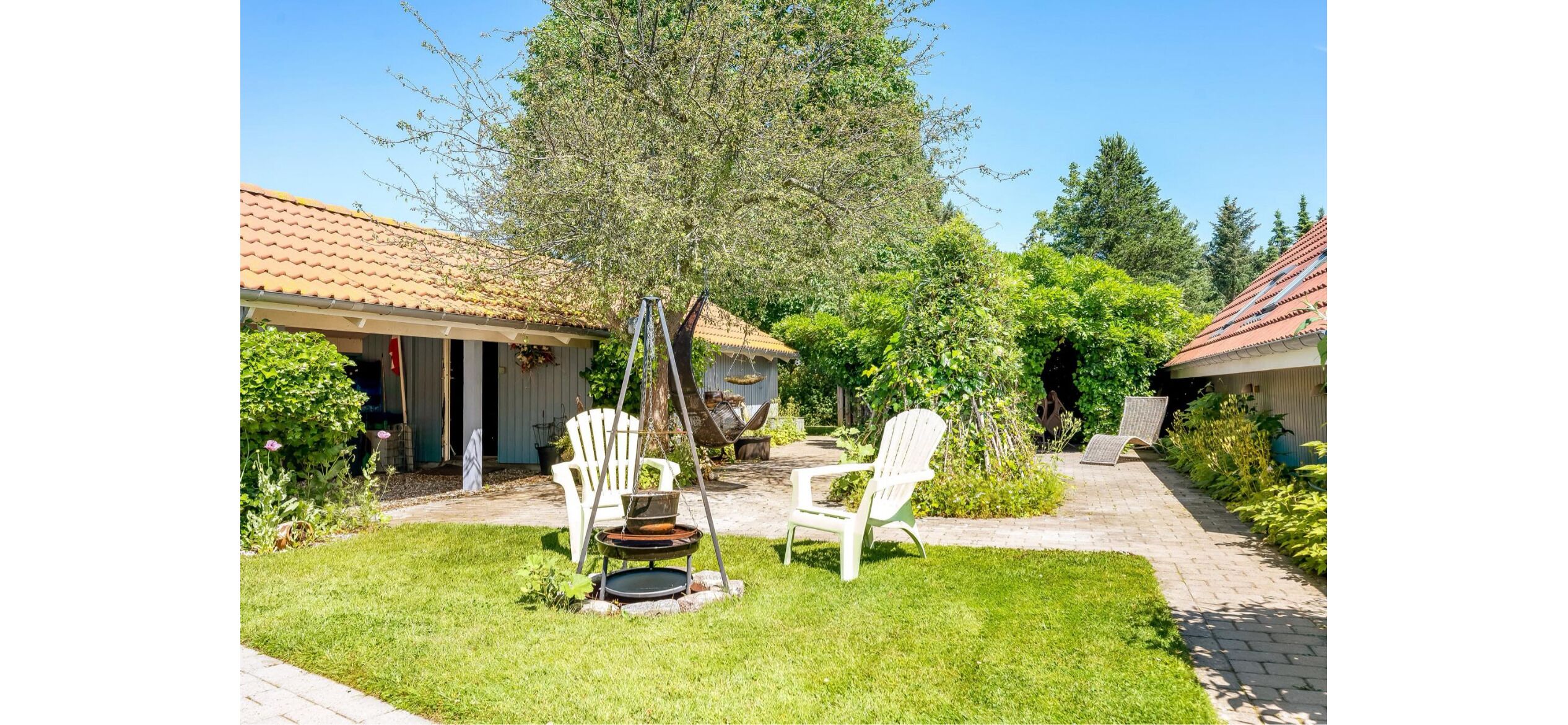 A patio with two white chairs, a small table, and a hanging chair.