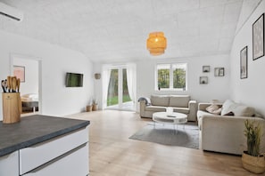 A spacious living area with a kitchen counter, two sofas, a coffee table, and a large window.