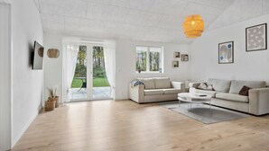 Ett modernt vardagsrum med en soffa, ett soffbord och en hängande lampa.