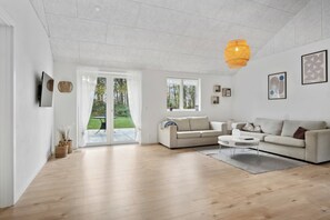 A modern living room with a sofa, coffee table, and a hanging light fixture.