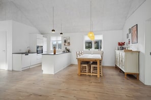 Une cuisine moderne avec des meubles blancs, un îlot central et des luminaires suspendus.