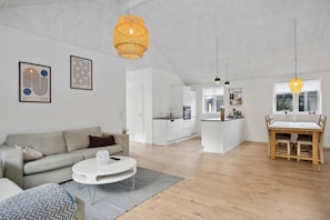 Un salon moderne avec un canapé, une table basse et des œuvres d’art accrochées au mur.
