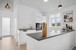 A modern kitchen with white cabinetry, a central island, and pendant lighting.