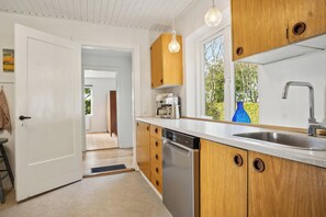 A modern kitchen with wooden cabinets, a dishwasher, and a large window.