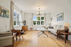 A living room with a wooden floor, a sofa, a coffee table, and a TV.