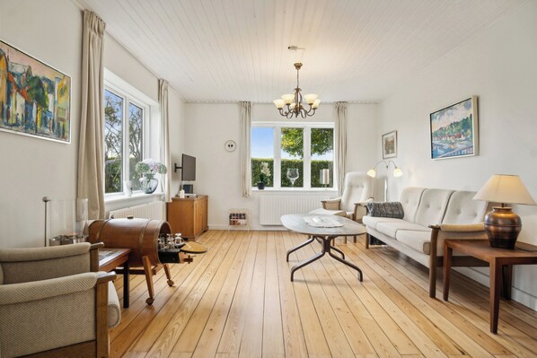 A living room with a wooden floor, a sofa, a coffee table, and a TV.
