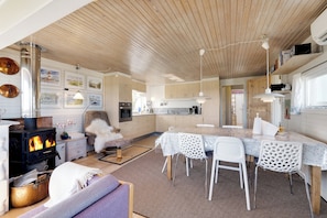 A cozy kitchen with a wood stove, white chairs, and a dining table. - 3 bedroom accommodation in Roslev (Roslev)