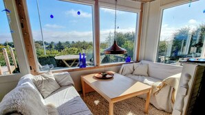 Une pièce confortable avec un canapé, une table et une vue dégagée grâce à de grandes fenêtres.