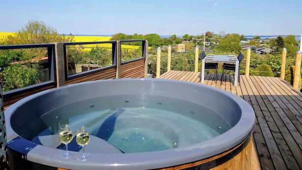 Un bain à remous sur une terrasse en bois, avec vue sur la campagne.