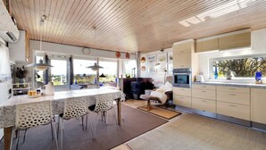 Une cuisine moderne avec un plafond en bois, un coin repas avec des chaises et une vue par la fenêtre.